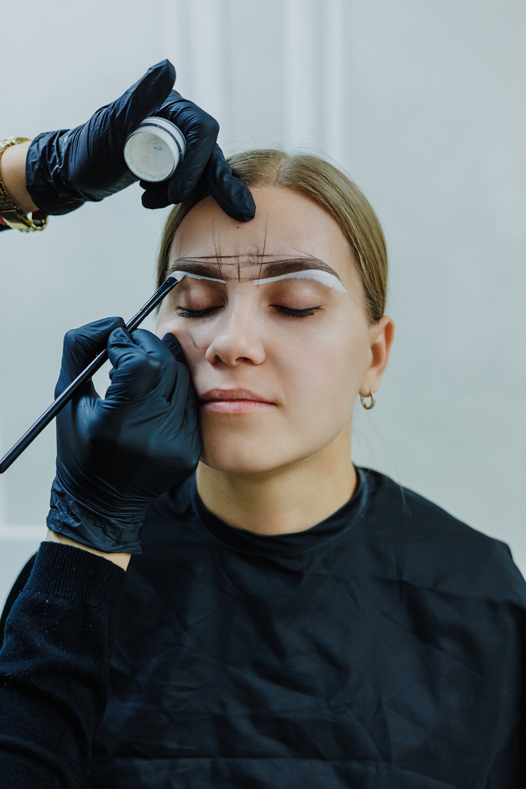 Young woman during professional eyebrow mapping procedure before permanent makeup