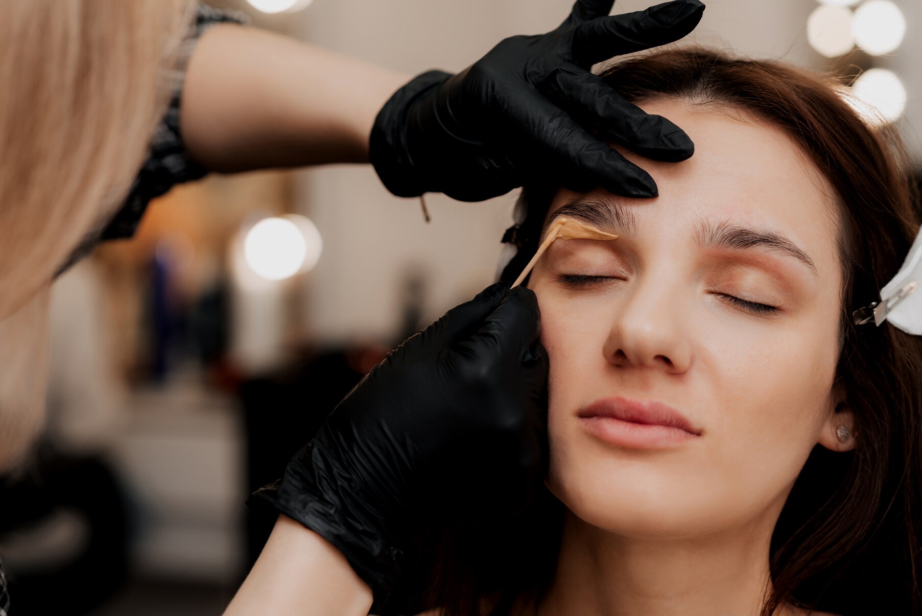 The Cosmetologist-Brovist Corrects and Gives Shape, Plucks Out Excess Hairs in the Eyebrows with Wax in the Beauty Salon. Professional Facial Care