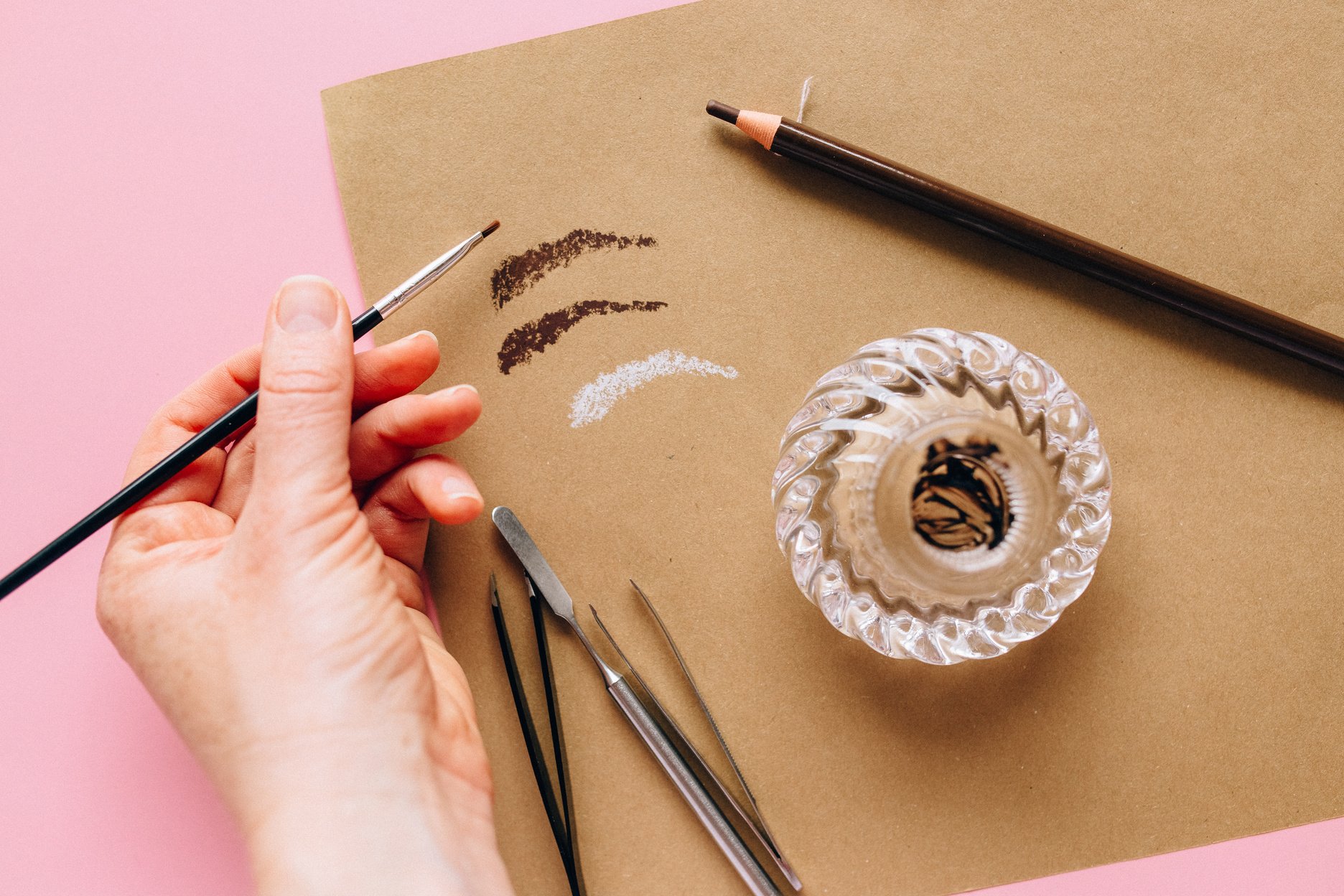 Person Holding Black Pen and White and Black Floral Textile